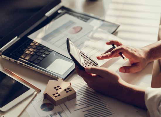 Hand of Business people calculating interest, taxes and profits to invest in real estate and home buying