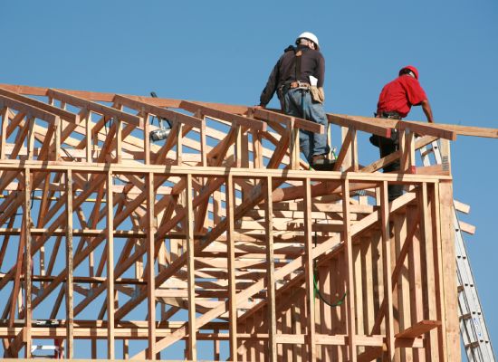 unidentifiable construction workers work on framing a building