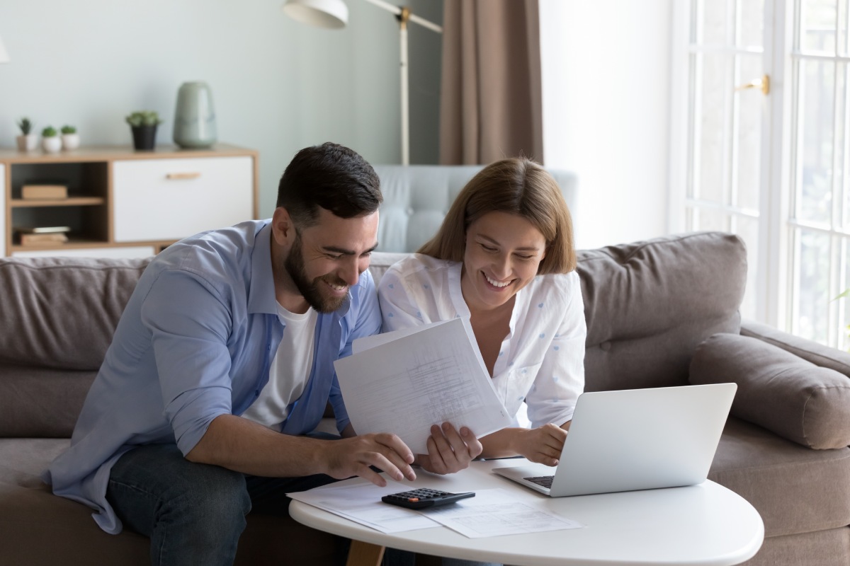 Cheerful young millennial husband and wife doing domestic paperwork