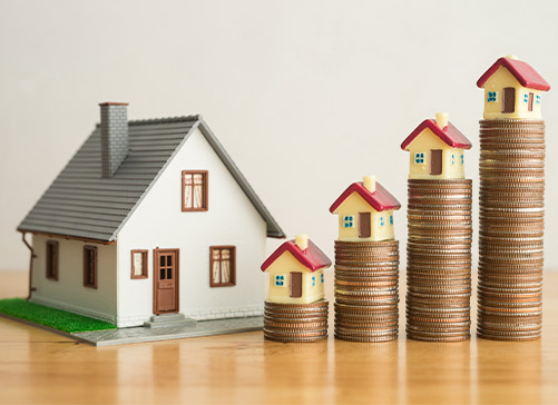 Una casa junto a monedas apiladas sobre una mesa, que representa las perspectivas financieras en la vibrante comunidad de McAllen.