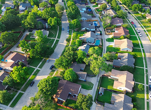 Vista aérea de un vecindario suburbano que muestra casas, calles y vegetación, destacando el encanto y la comunidad de McAllen.