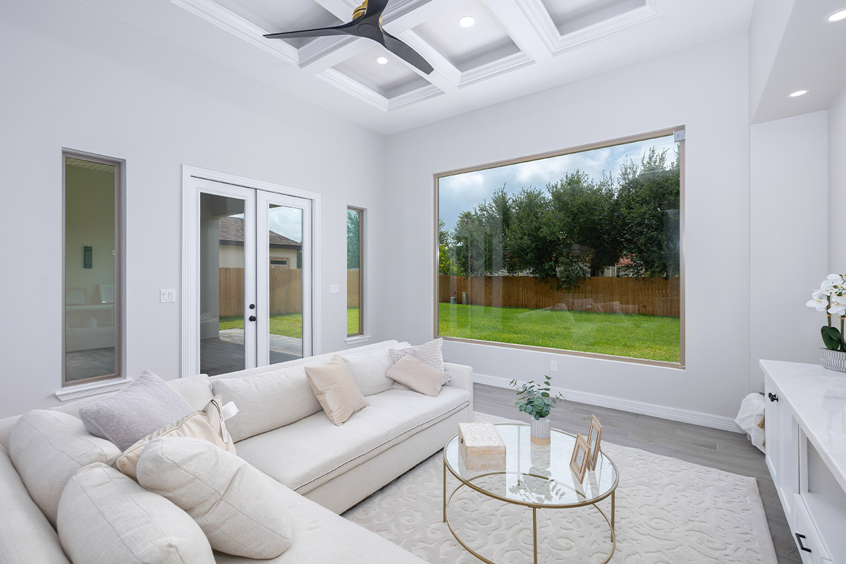 Elegant living room with white furniture and a spacious window, highlighting luxury home features and upgrades.