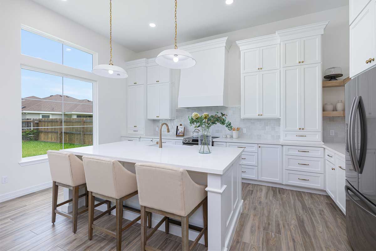 Bright kitchen with white cabinetry and a central island, showcasing a stylish layout relevant to custom home construction in Brownsville, TX.