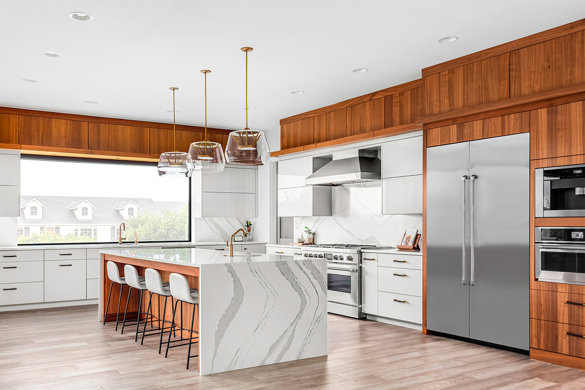 A stylish kitchen with a large central island and a contemporary refrigerator, highlighting Texas home renovation trends.