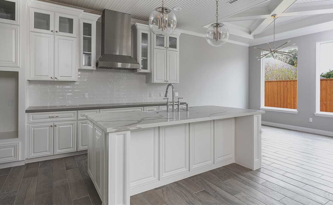 Spacious kitchen with white cabinetry and warm hardwood flooring, emphasizing a contemporary aesthetic.