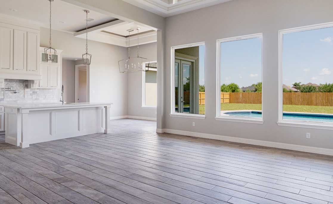 Open-concept living room with hardwood flooring and expansive windows, enhancing natural light and spaciousness.