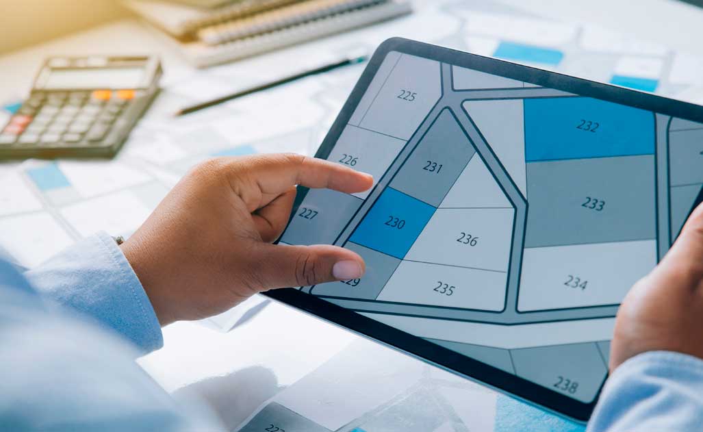 Man holding a tablet looking at lots of lands. Land plot management - real estate concept with vacant land for building construction and housing subdivision for sale, rent, buy, or investment