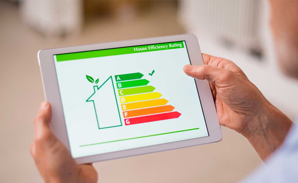 Hand holding digital tablet and looking at house efficiency rating. Detail of house efficiency rating on digital tablet screen. Concept of ecological and bio energetic house. Energy class.
