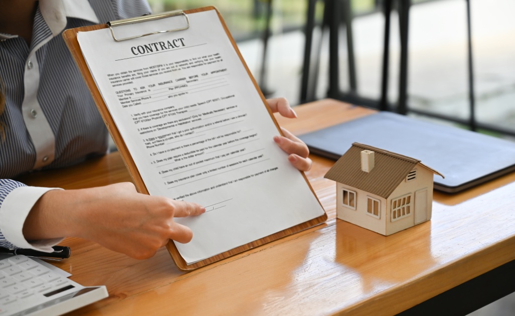 A professional showcasing a contract for signing alongside a house model, symbolizing trust and transparency in home-building services.